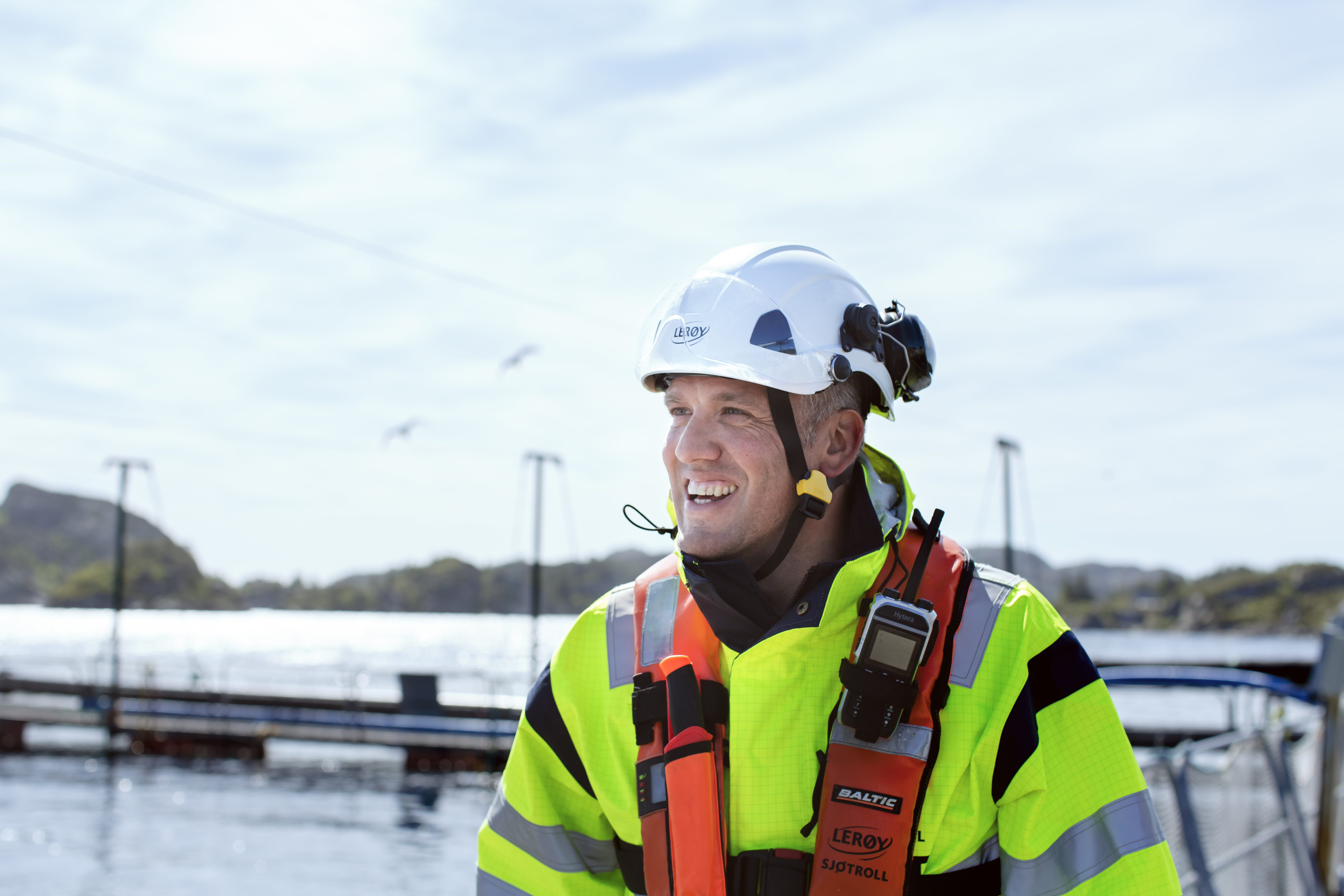 Lerøy employee in workwear and safety equiptment outside by an aquaculture faciltity