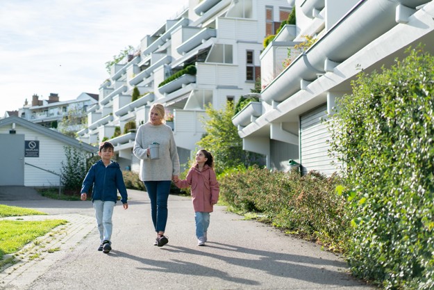 Tre bøssebærere går sammen i et nabolag. To unge barn og en voksen dame. 